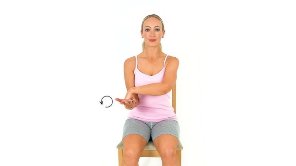 Person seated performing a forearm rotation exercise to improve elbow mobility.