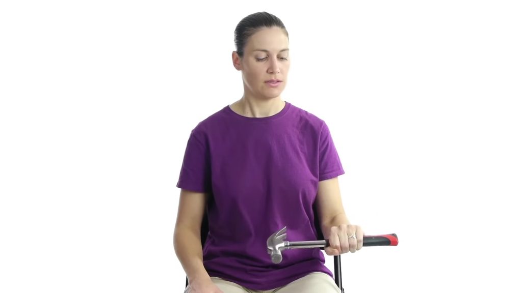 Person performing a grip strengthening exercise using a handheld weight to condition the forearm and elbow.