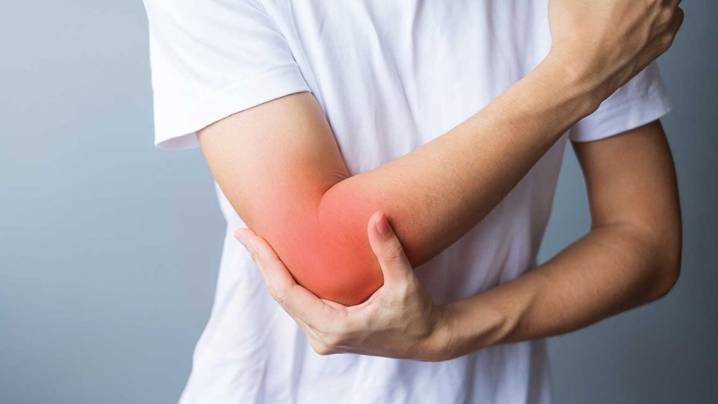 Person holding a painful elbow with redness highlighting elbow inflammation.