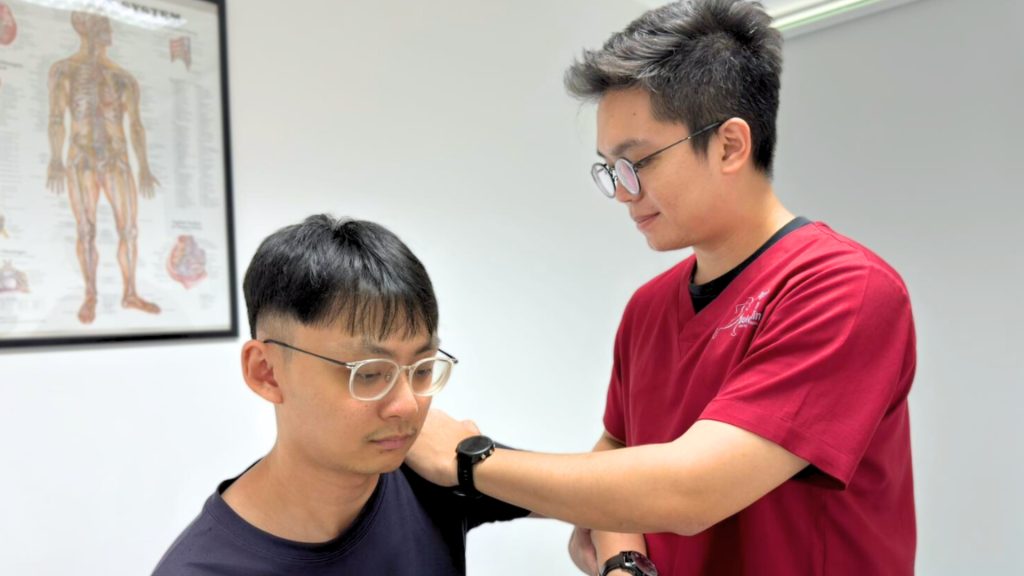 Physiotherapist assessing a patient’s elbow during a clinic consultation.