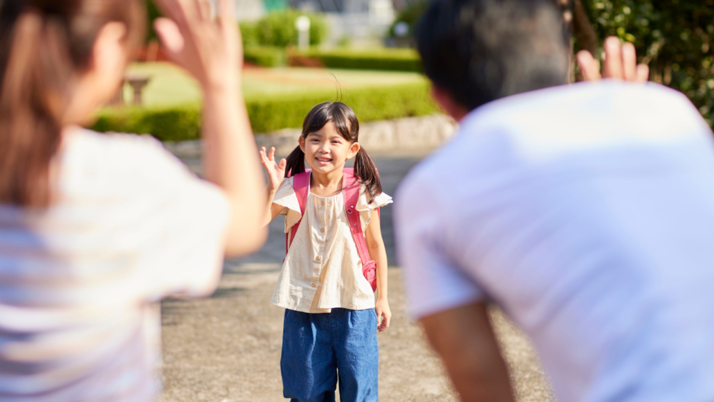 Smiling primary school child waving goodbye to parents before school, highlighting everyday movement and activity in growing children.