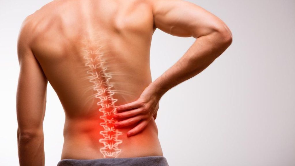 Man holding his lower back with highlighted spine, illustrating lower back pain.
