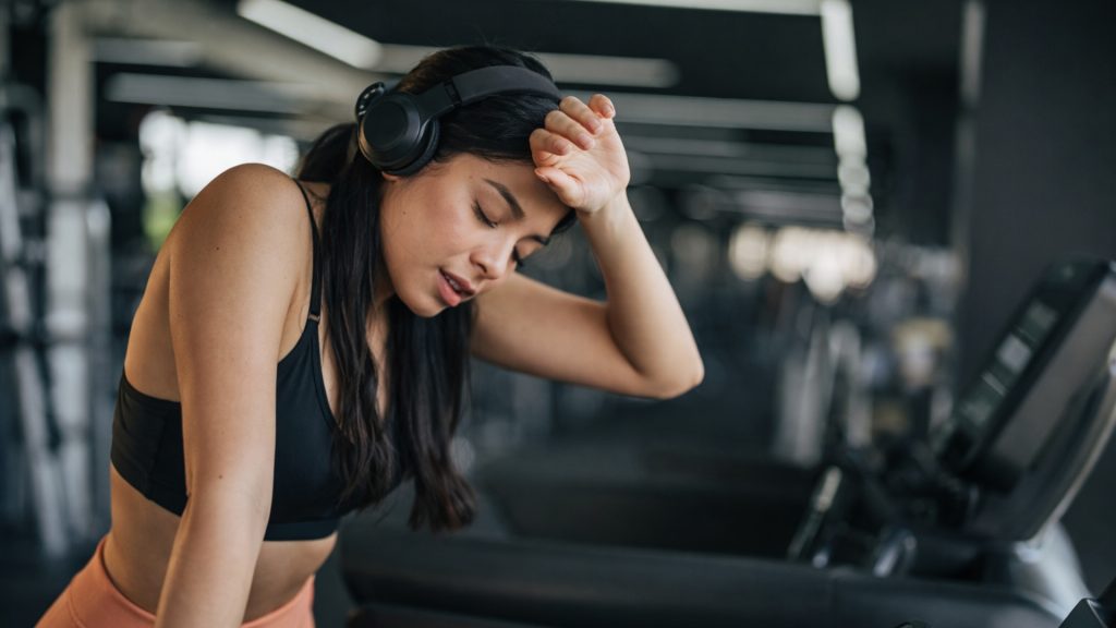 Runner pausing on a treadmill, appearing fatigued and uncertain during a workout.
