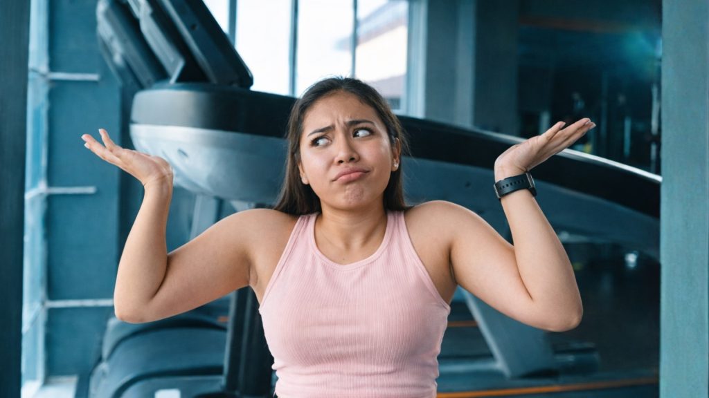 Runner shrugging in a gym, expressing uncertainty about the cost of gait analysis.
