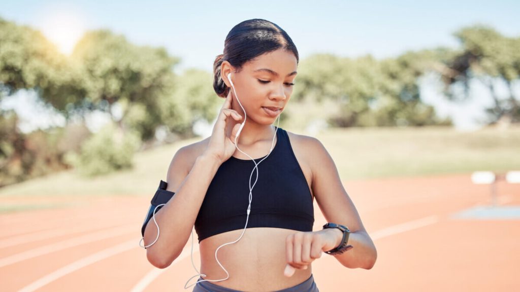 Runner checking her smartwatch on a running track.
