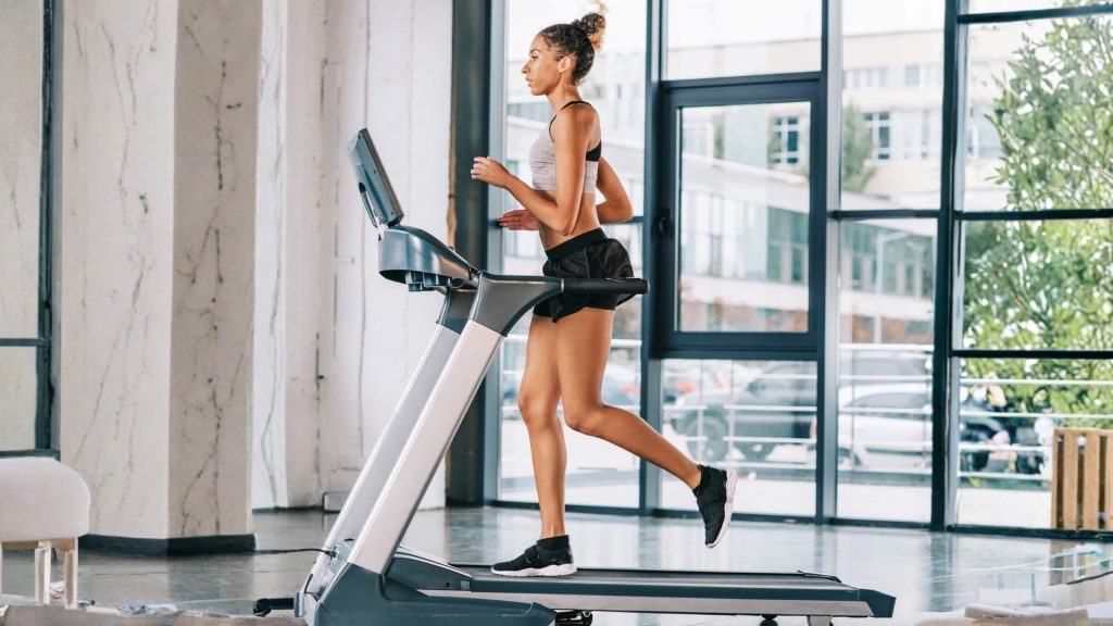 Runner jogging on a treadmill in a gym, illustrating indoor running mechanics during training.
