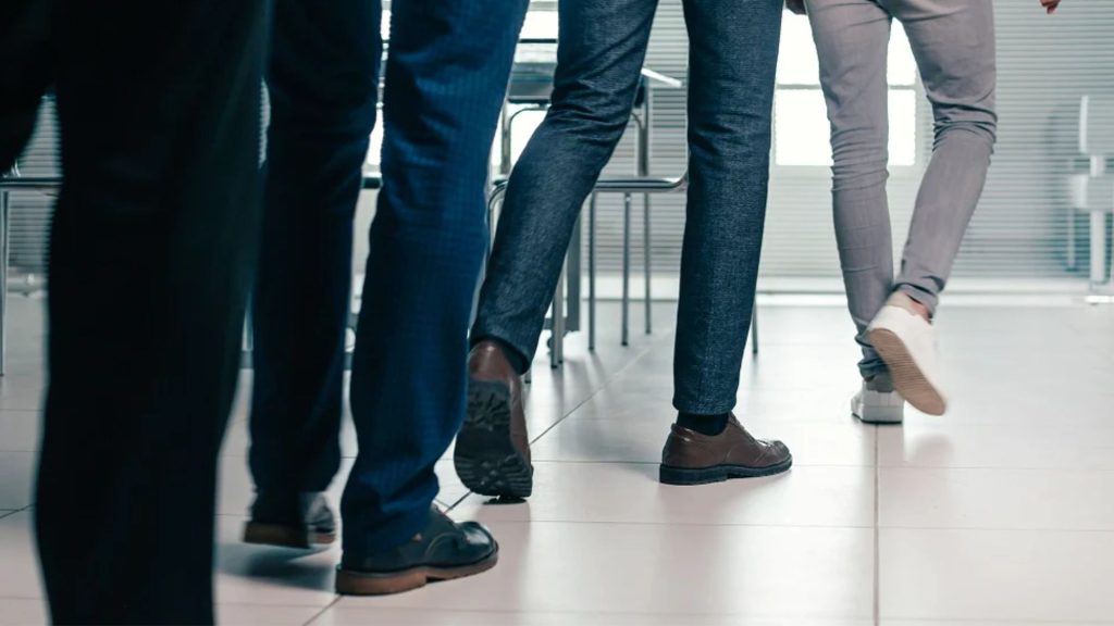 Office workers walking indoors wearing covered work shoes, reflecting long hours spent in enclosed footwear.