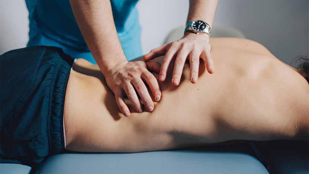 Physiotherapist applying hands-on treatment to the lower back during a therapy session.