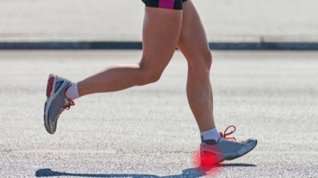 Runner mid-stride on a road with a red highlighted area under the heel, illustrating plantar fasciitis and repetitive heel stress during running.