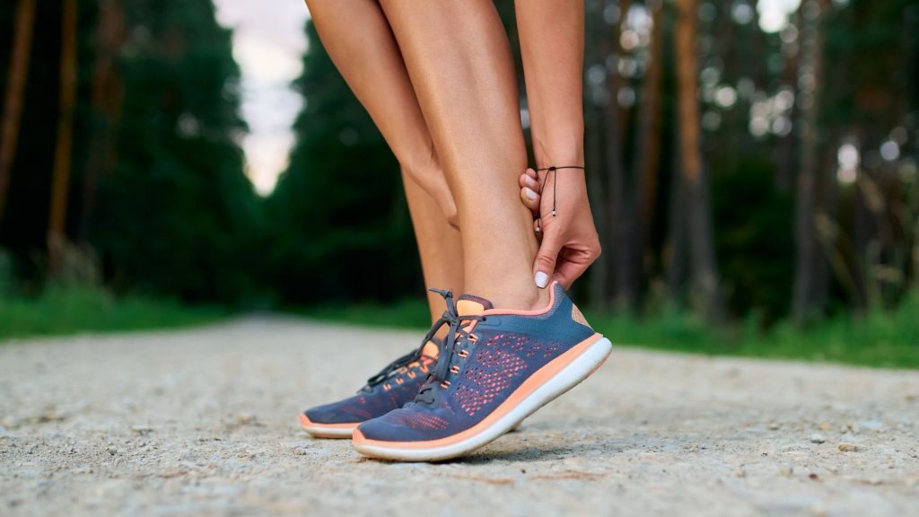 Runner holding the back of the heel, showing Achilles tendon pain commonly experienced during or after running