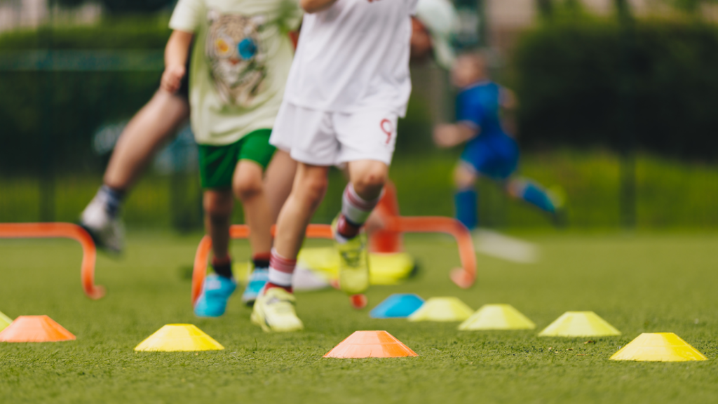 Young children participating in agility drills on a field, highlighting foot strength, coordination, and movement during sports.