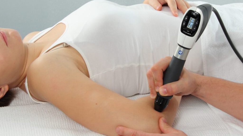 Clinician performing shockwave therapy on a patient’s elbow to treat tendon pain.
