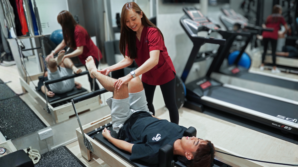 Physiotherapist assisting a patient with a lower limb exercise during a rehabilitation session.