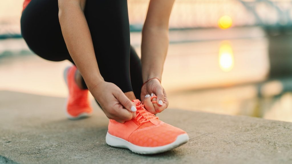 Active adult tying running shoes, illustrating footwear pressure that can contribute to ingrown toenails.
