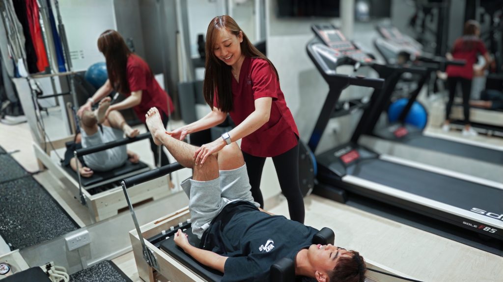Physiotherapist assisting a senior patient with lower limb strengthening exercises during rehabilitation.
