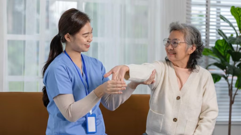 Physiotherapist guiding an elderly woman through arm mobility assessment in a treatment room.
