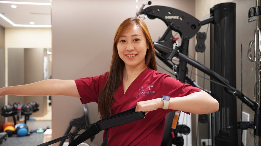 Physiotherapist demonstrating resistance band exercise for shoulder and upper limb strength.
