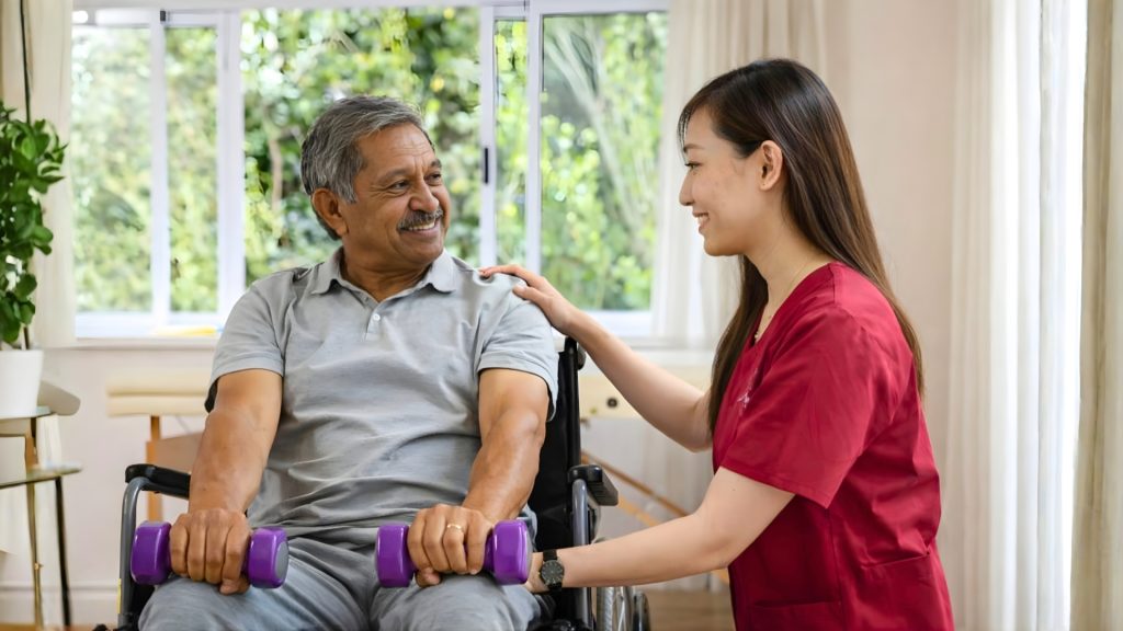 Physiotherapist supporting a senior patient performing seated strength exercises with dumbbells.
