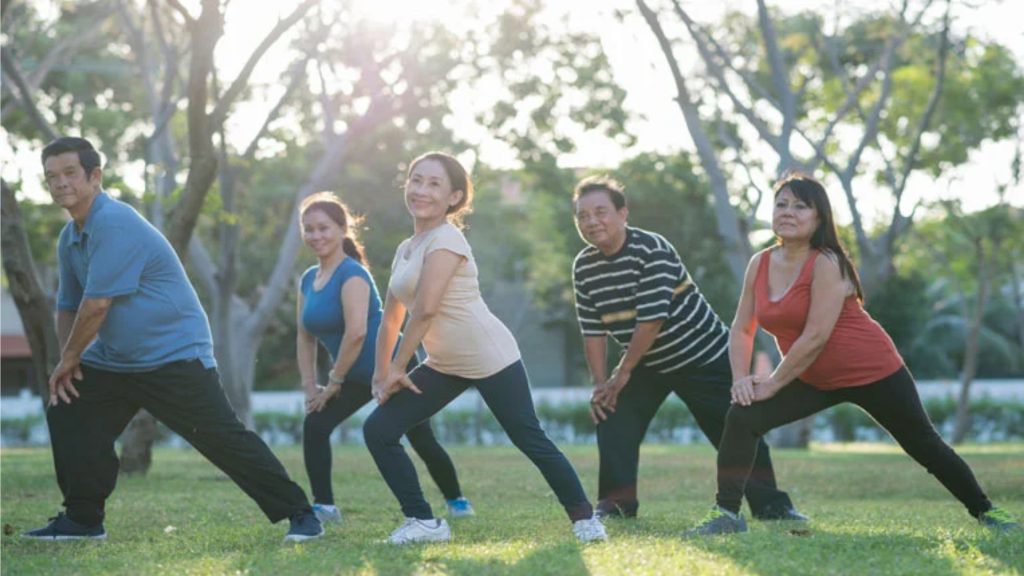 Group of seniors performing guided stretching exercises outdoors to improve mobility, balance, and joint flexibility.
