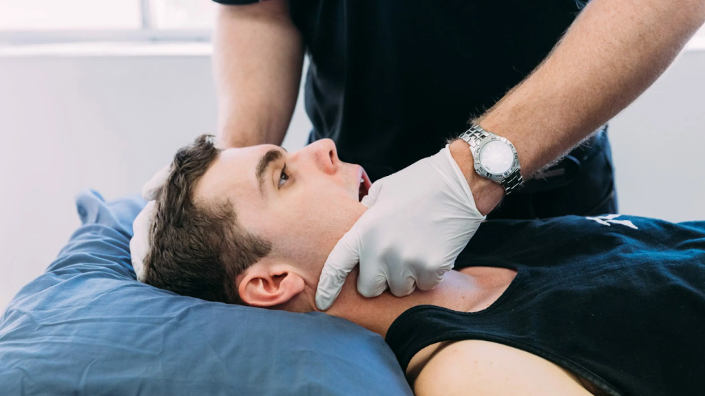 Physiotherapist assessing jaw movement in patient during temporomandibular joint examination.