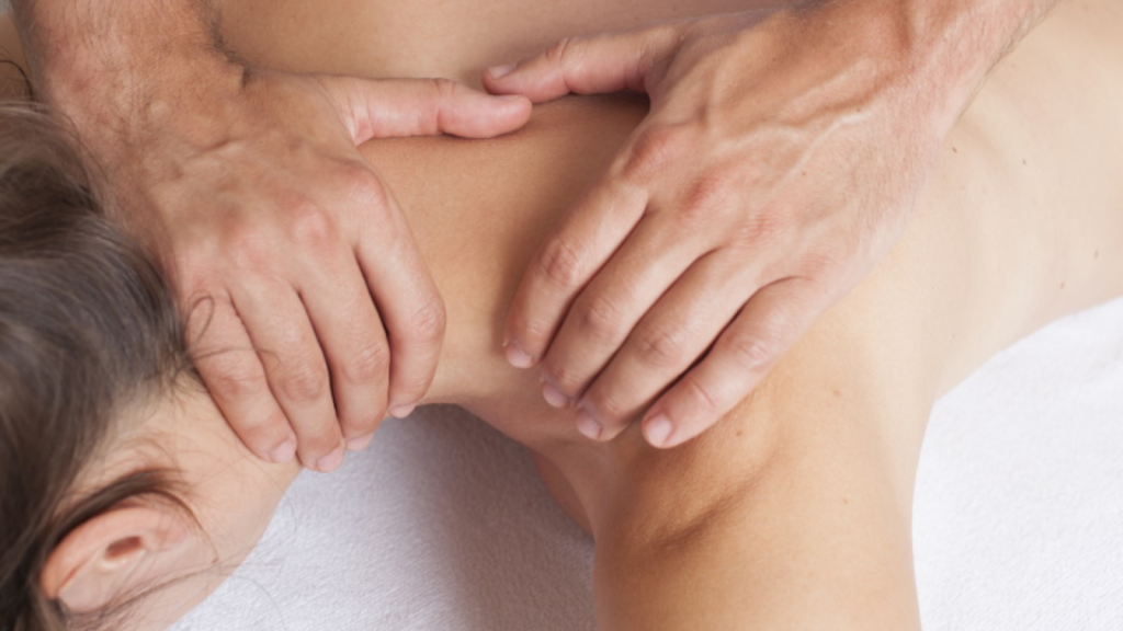 Close-up of therapist performing neck massage treatment on patient