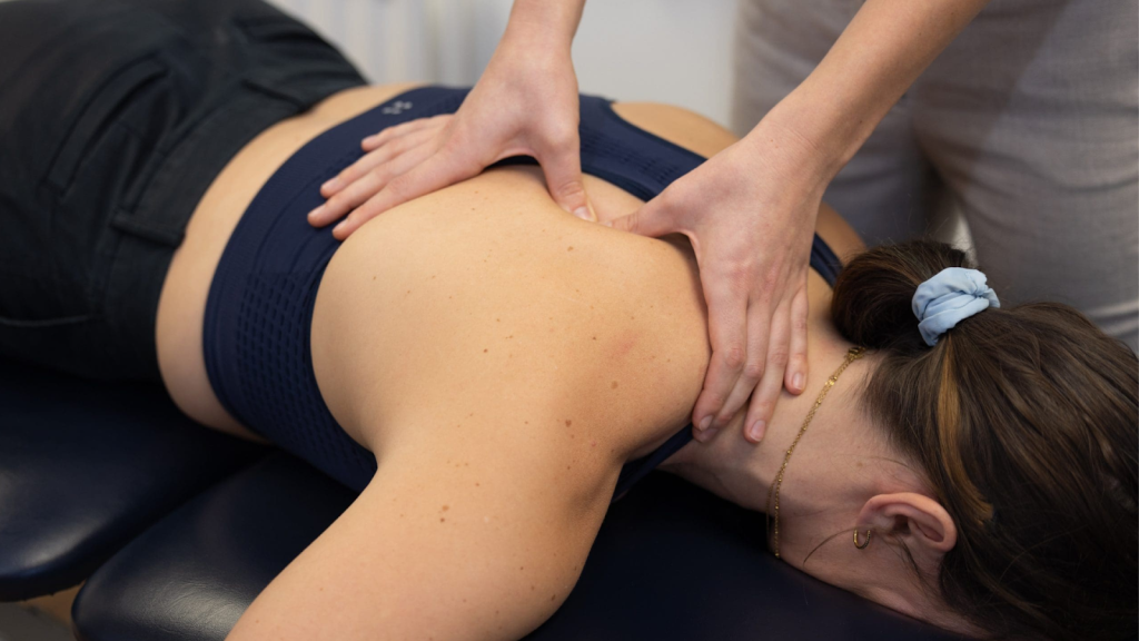 Therapist applying soft tissue pressure to upper back during hands-on treatment