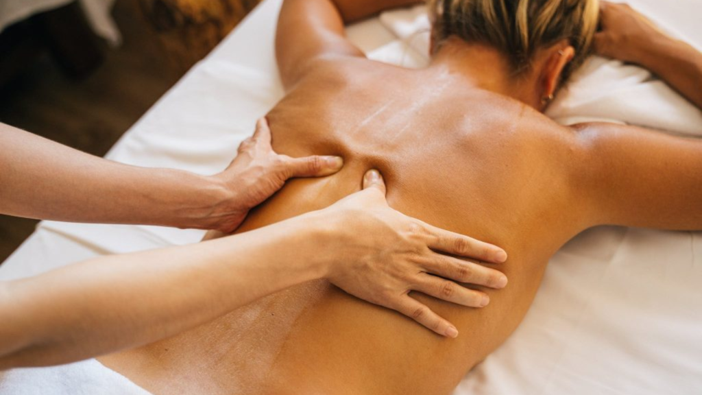 Massage therapist applying pressure to upper back during spa massage treatment
