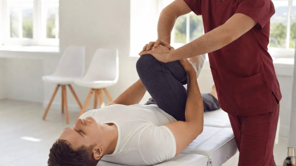 Therapist performing assisted knee flexion stretch on patient during post-ACL rehabilitation session.
