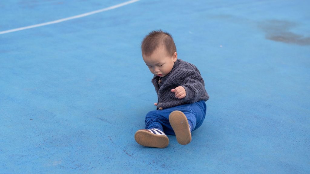 child sitting on playground after falling which may indicate balance issues related to foot mechanics