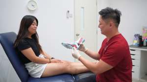 podiatrist Singapore explaining foot muscles using anatomy model during foot assessment
