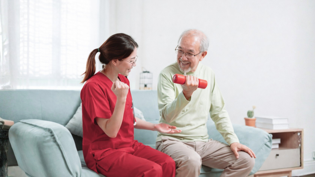 Physiotherapist and senior man smiling while performing arm strengthening exercise with dumbbell at home.
