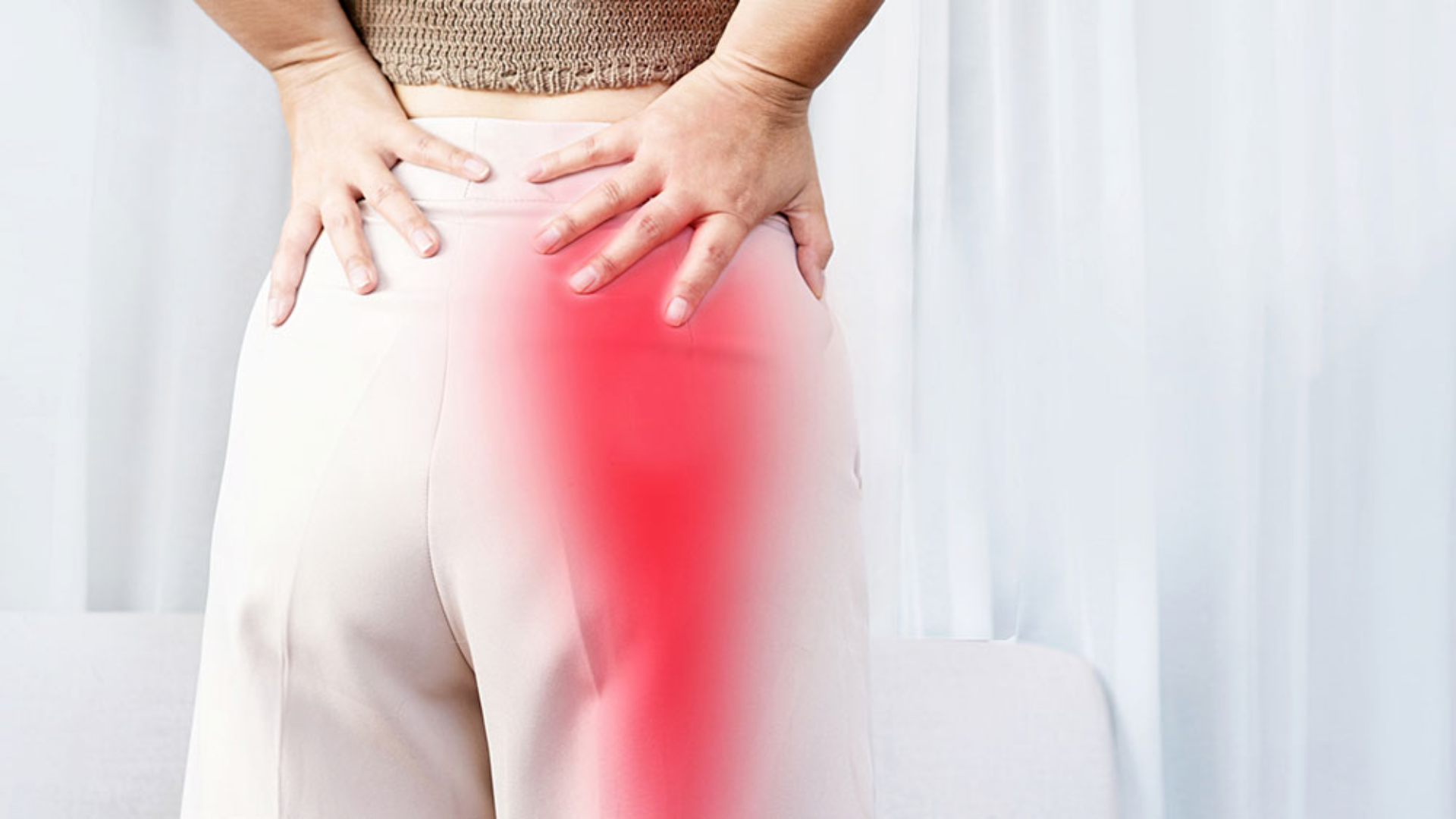 Person holding lower back and hip with highlighted red area indicating sciatica pain radiating down the leg