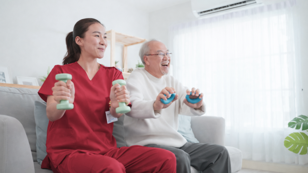 Physiotherapist and elderly man doing seated strengthening exercises with small weights. 