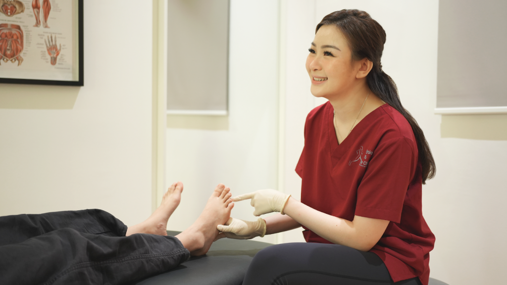 Podiatrist examining a patient’s foot during a consultation in a clinic treatment room.