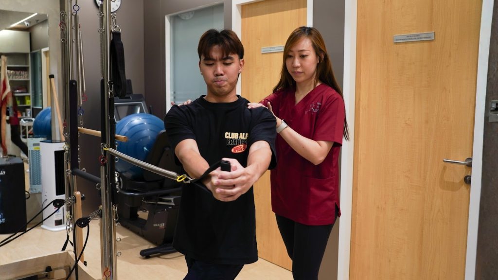 Physiotherapist guiding patient with resistance band exercise in clinic.
