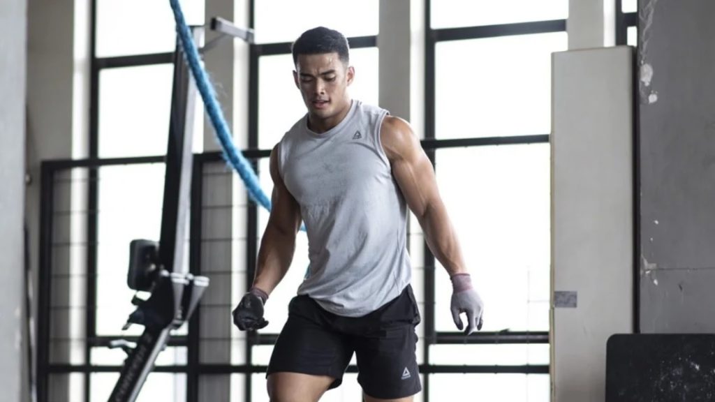 Hybrid athlete training in gym performing lower body strength movement.
