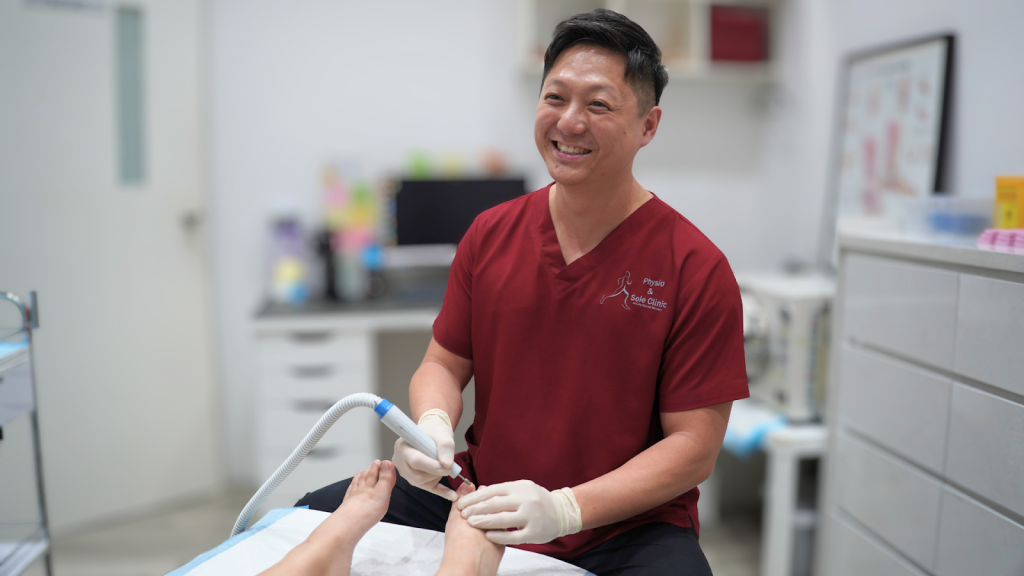 Physiotherapist performing foot treatment using a handheld device on a patient’s heel in a clinical setting, demonstrating professional care for plantar fasciitis