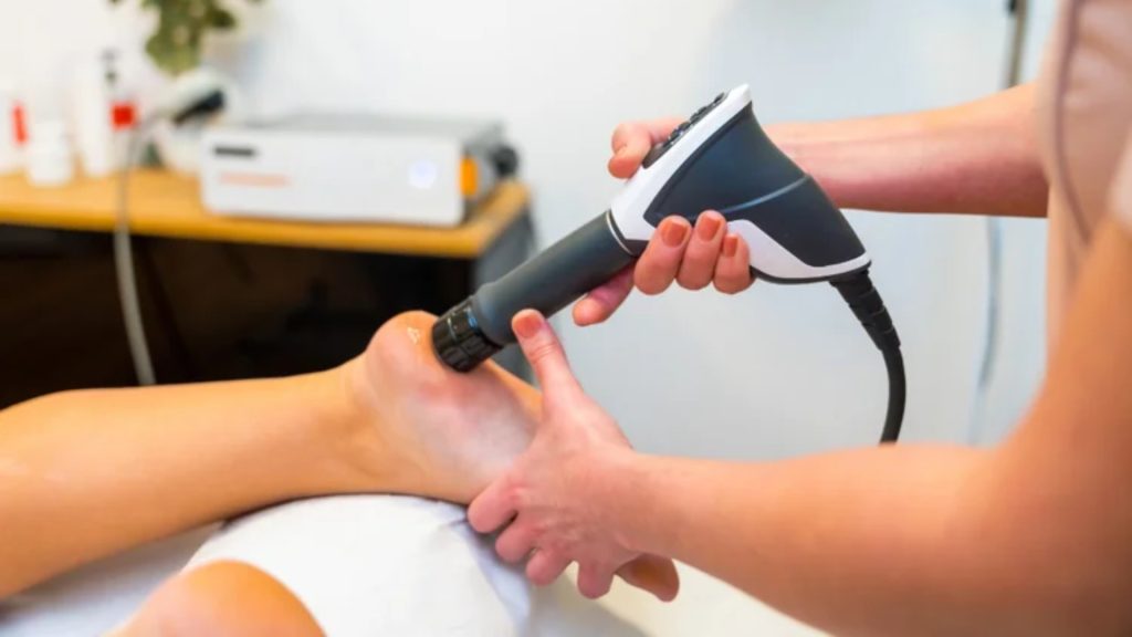 Close-up of shockwave therapy device treating inflamed tendon in heel.
