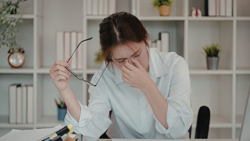 office worker experiencing tension headache and eye strain linked to poor workstation posture Singapore physiotherapy advice