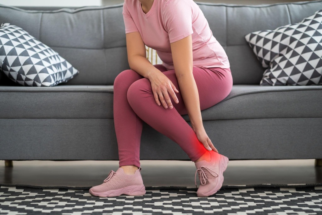 adult experiencing lower leg pain holding calf muscle discomfort at home