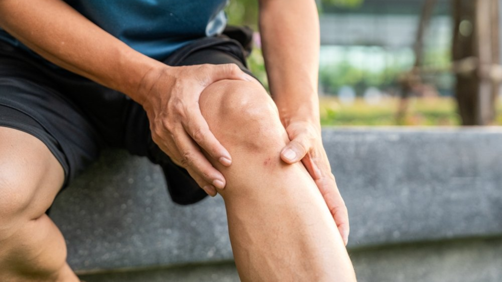 Person holding a painful knee due to injury, highlighting the importance of early physiotherapy treatment
