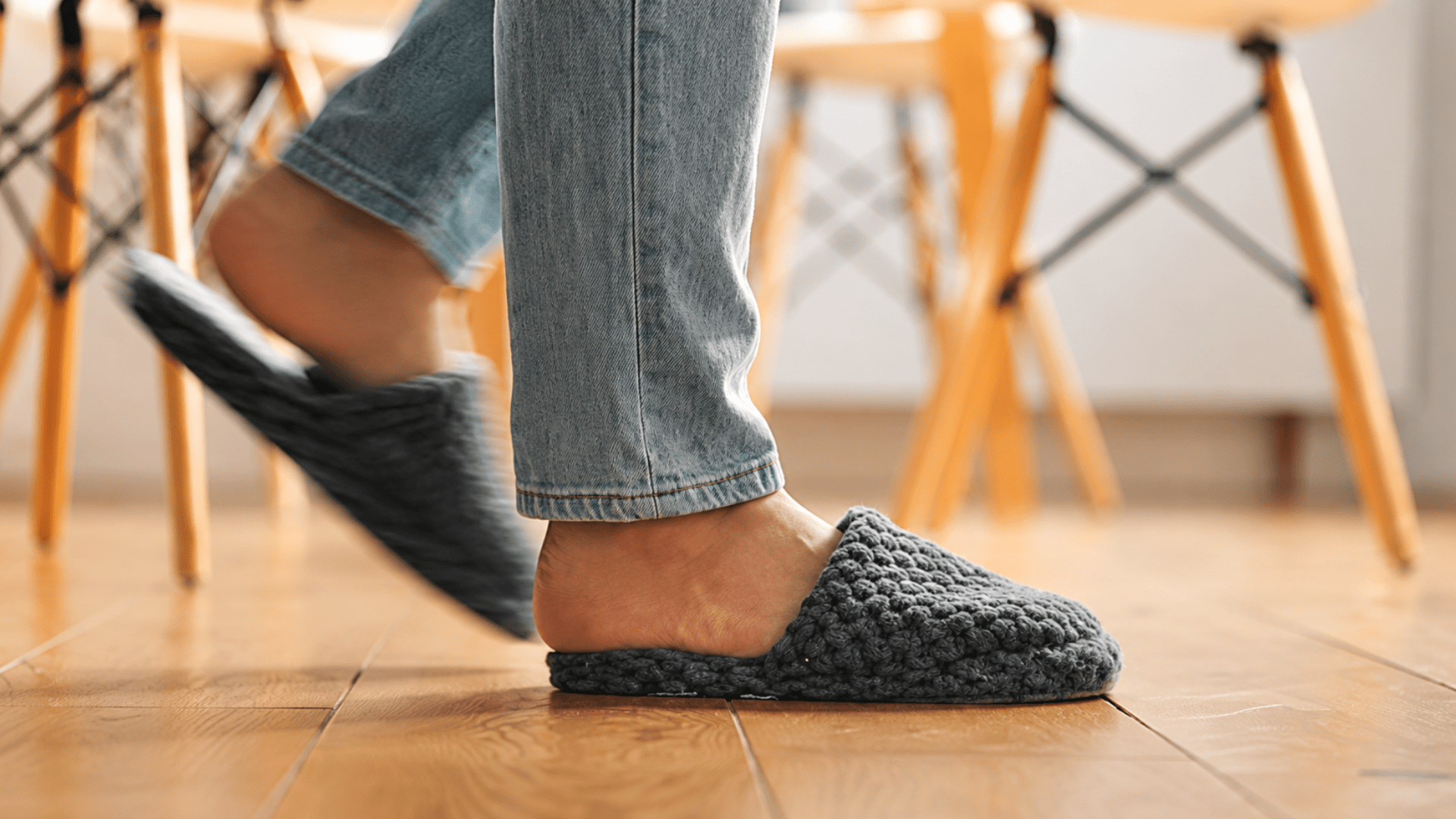 Person wearing soft indoor slippers while walking on hard home flooring, illustrating everyday home footwear and foot support for flat feet.